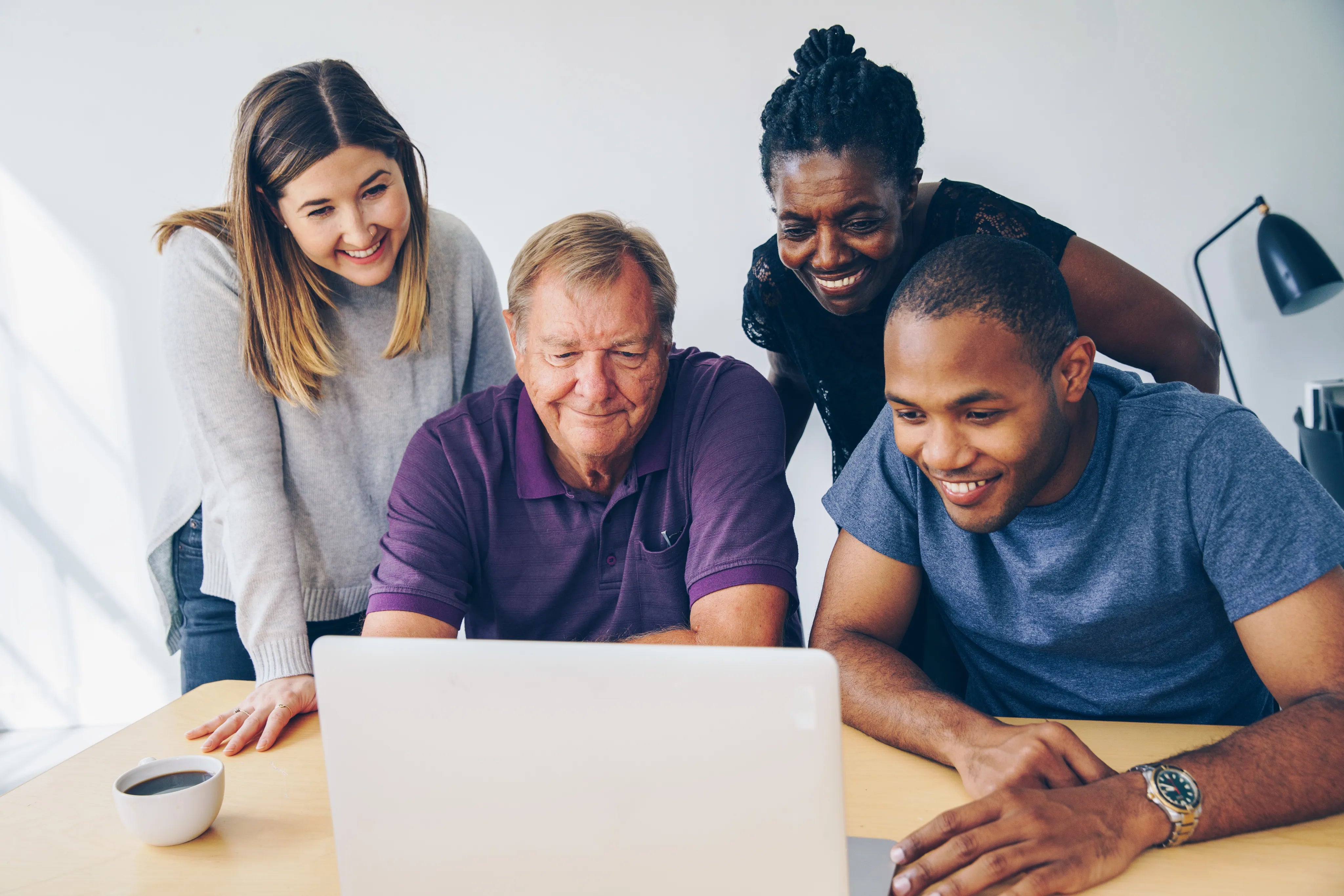 Diverse team around laptop smiling